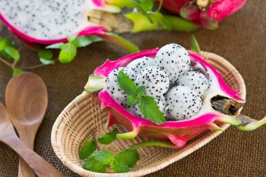 Imagen de una mesa con cuencos de madera y fruta del dragón.