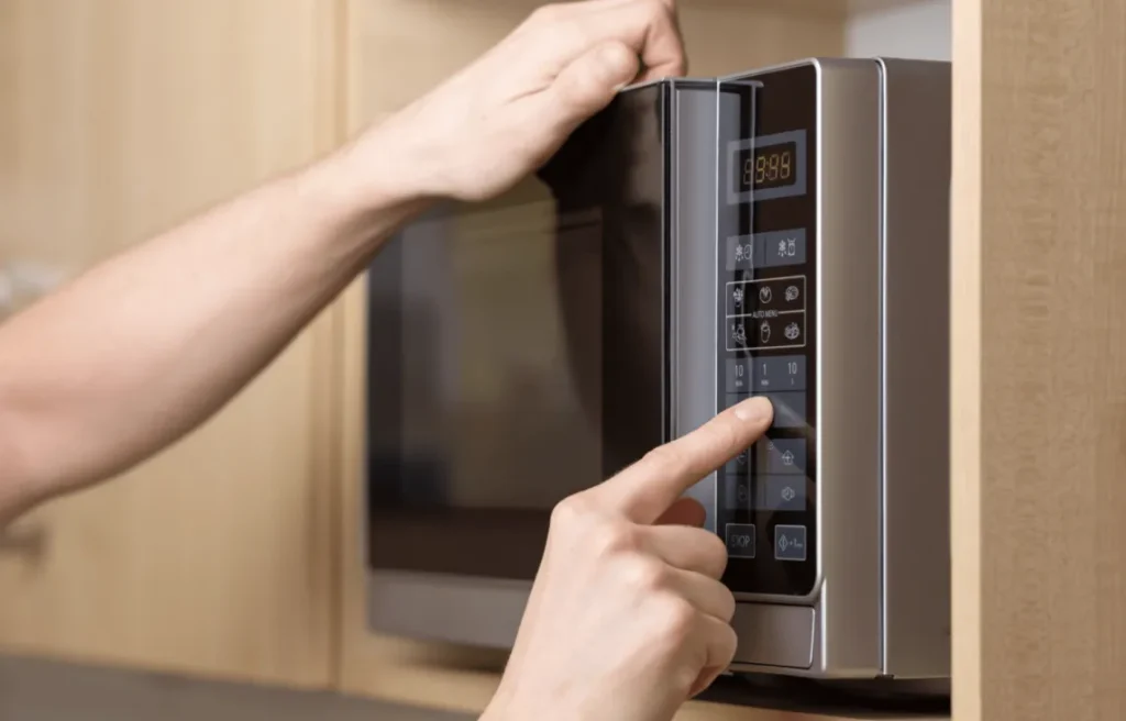 Persona ajustando el panel digital de un microondas para seleccionar el tiempo o la función de cocción.