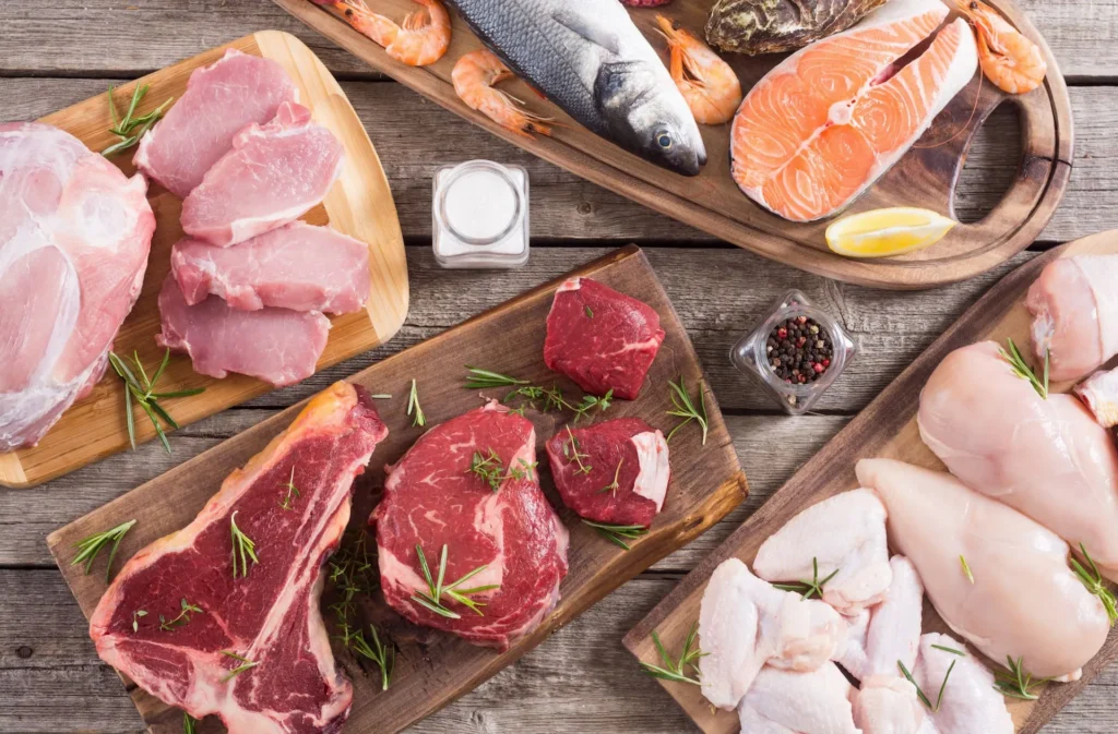Mesa puesta con diversas proteínas alimenticias: carnes blancas, carnes rojas y pescado.