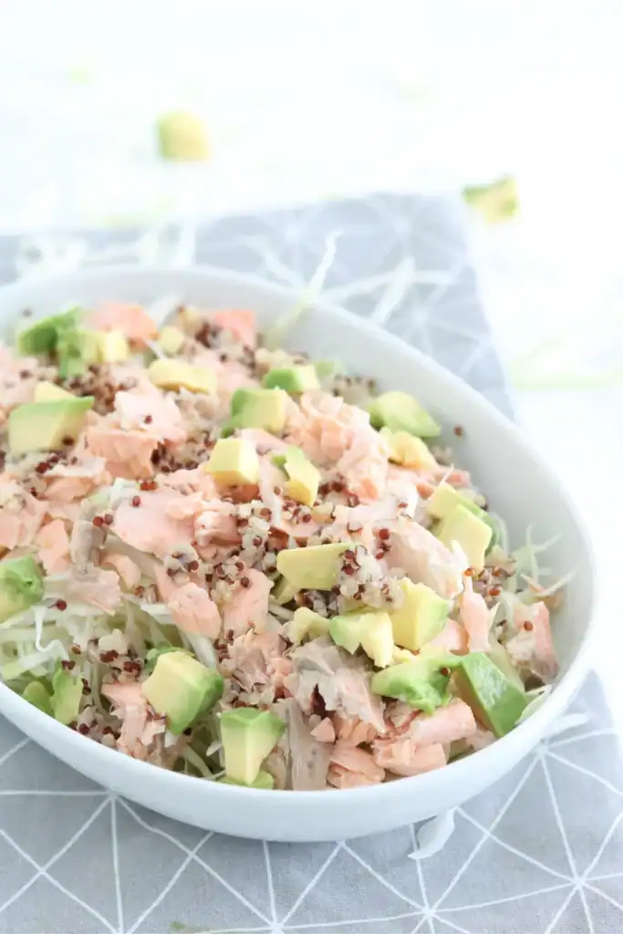 Ensalada de quinoa con salmón fresco, aguacate y verduras en cuenco blanco