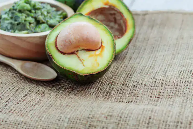 Aguacate cortado a la mitad junto a guacamole casero
