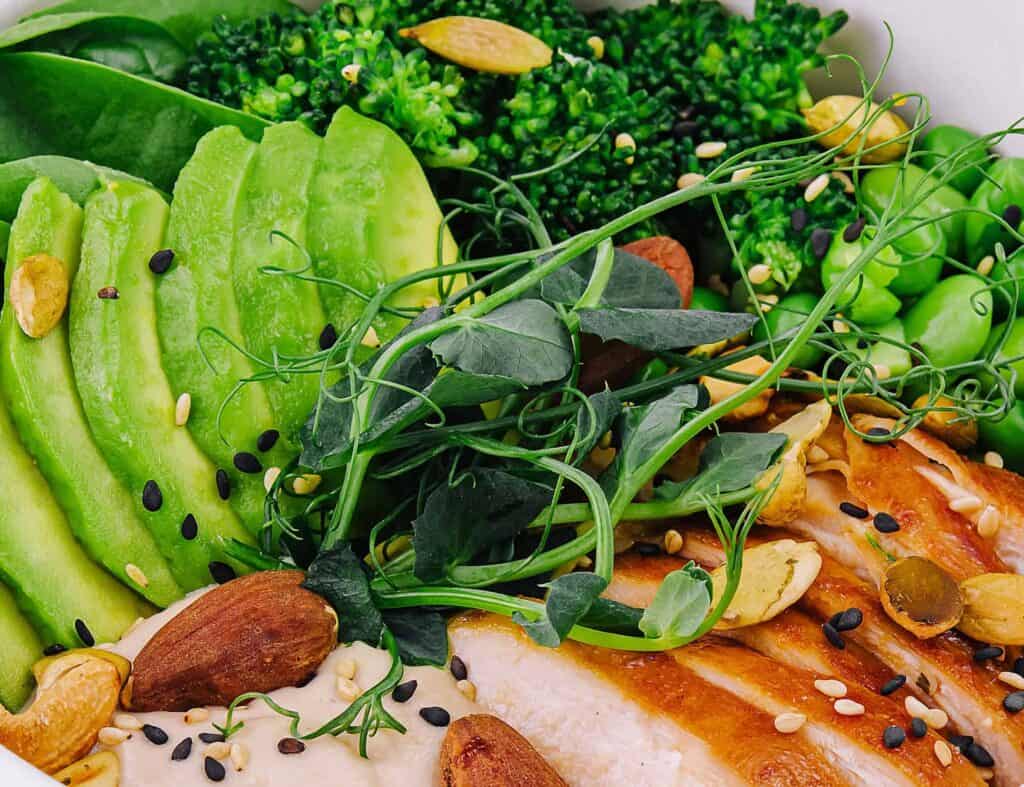 Bol con pechuga de pollo, edamame, aguacate, brócoli, hummus y frutos secos, fuentes de proteínas animales y vegetales.